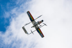 An Apian drone in flight, from below. The drone has NHS logos and rainbow flags on its wings.